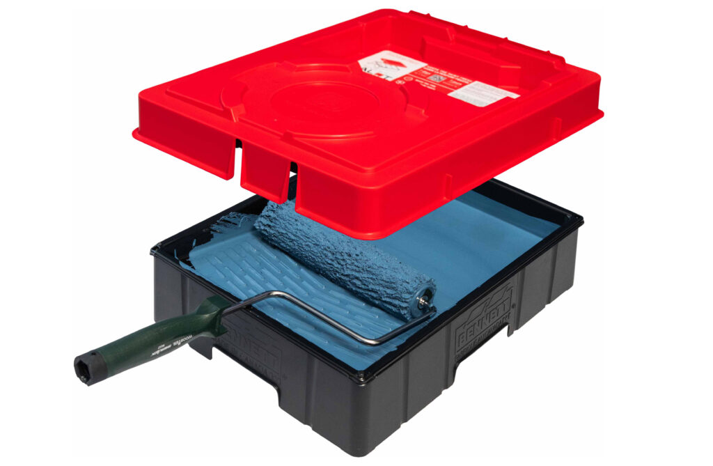 A view of the inside of a paint train filled with white paint and a roller, while a Red PALOT TRAY PAL lid hovers over top.